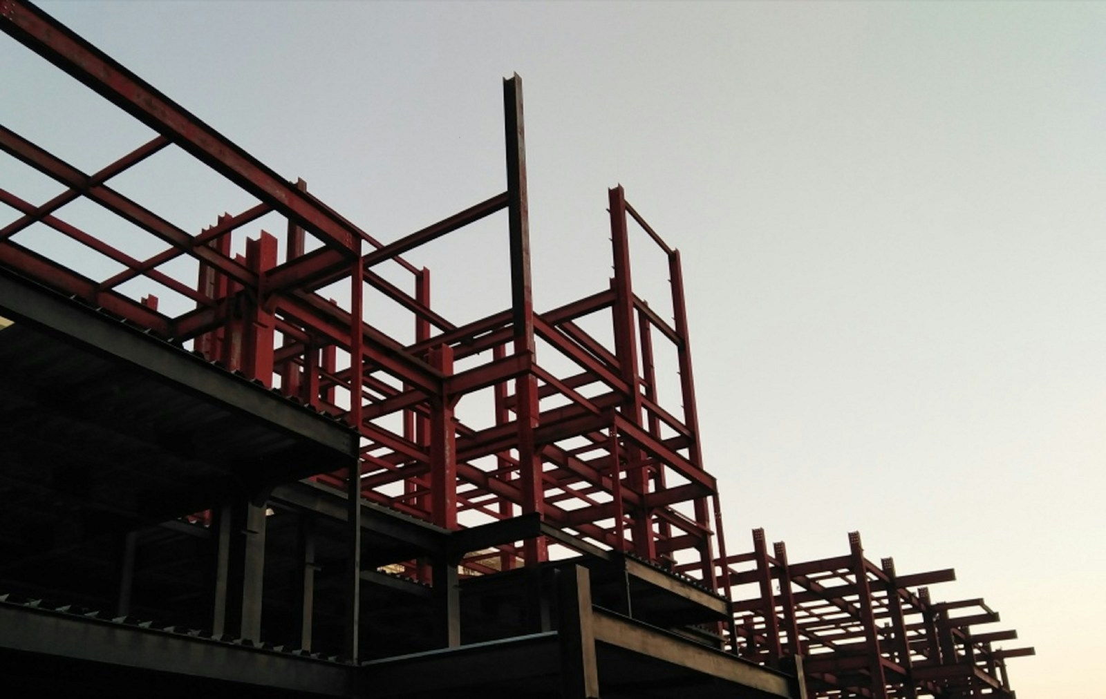 Rangka baja konstruksi merah saat tahap erection di lapangan
