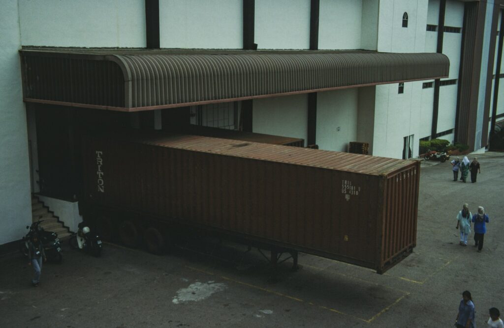 Truk kontainer bersandar di loading dock pabrik berkanopi