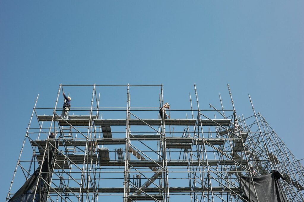 Pekerja memasang perancah di lokasi proyek konstruksi baja