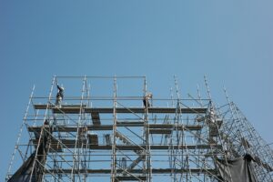 Pekerja memasang perancah di lokasi proyek konstruksi baja